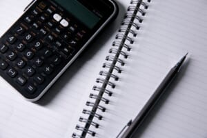 開いたノートと電卓、ペンを並べた机